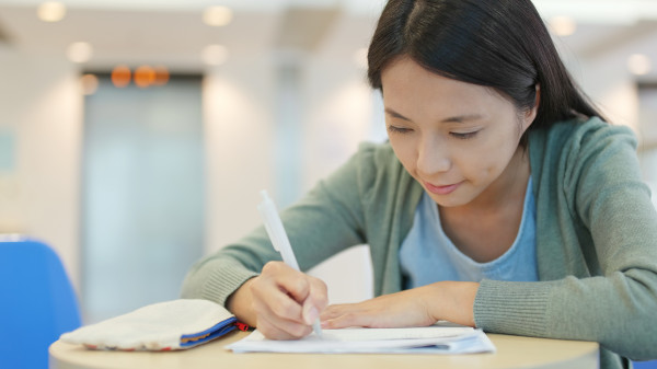 student writing on her note at school