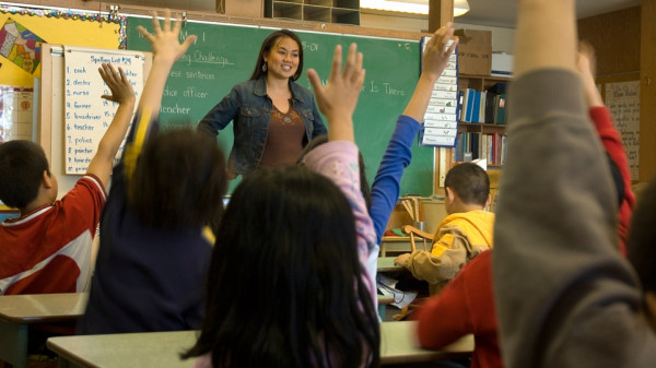 students raising hands in classroom