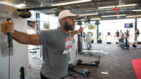 Man wearing Ohio State shirt in the weight room working out.