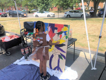 Young girl painting under a tent on a sunny day