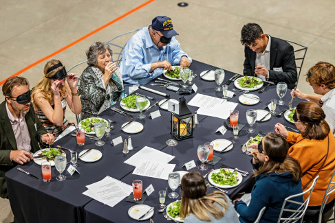 Attendees, some wearing eye covers, participating in the "Dining in the Dark & Dim" event