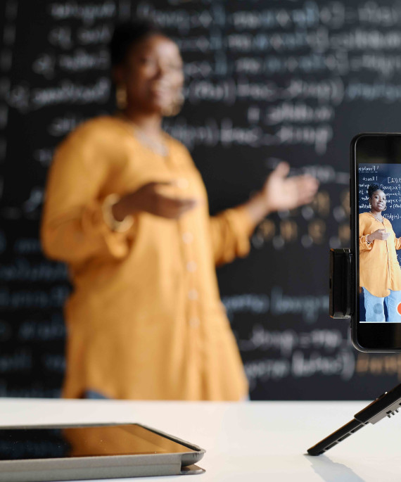 Woman teaching in front of a blackboard while being recorded