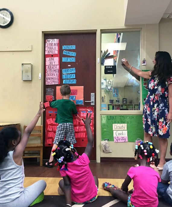 a teacher in a classroom speaking to a group of young students