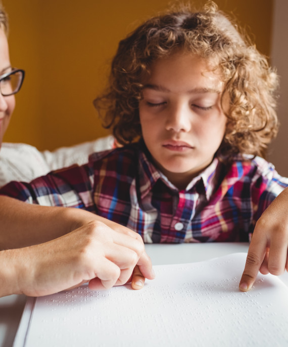 Teacher helping student read braille