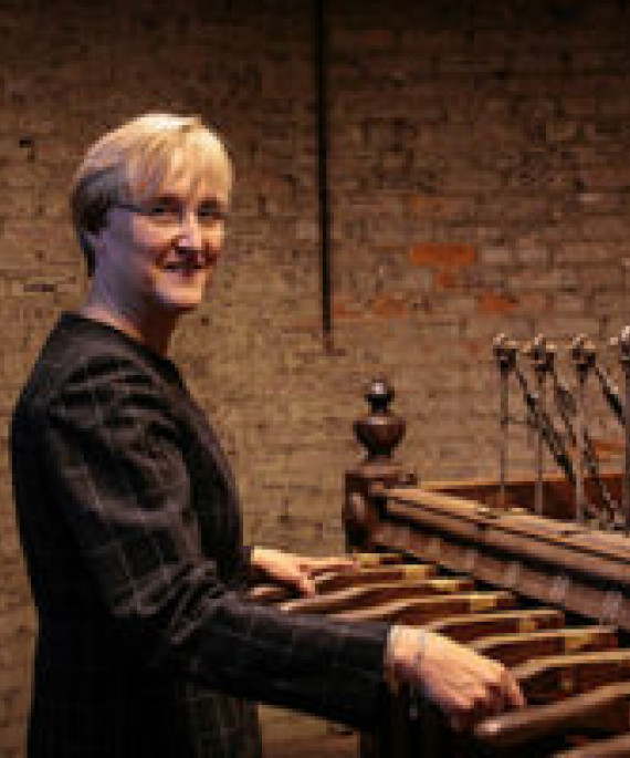 Cathy Montalto standing in front of a bells musical instruments