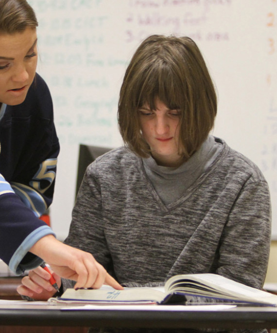 teacher pointing to book with student