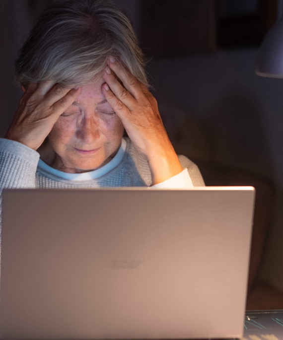 older women alone at her computer looking stressed