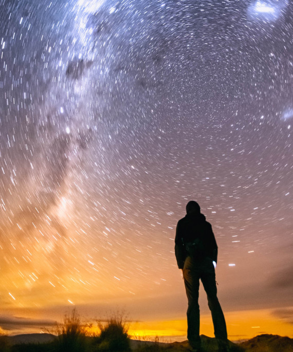 hiker silhouetted against the starry night sky 