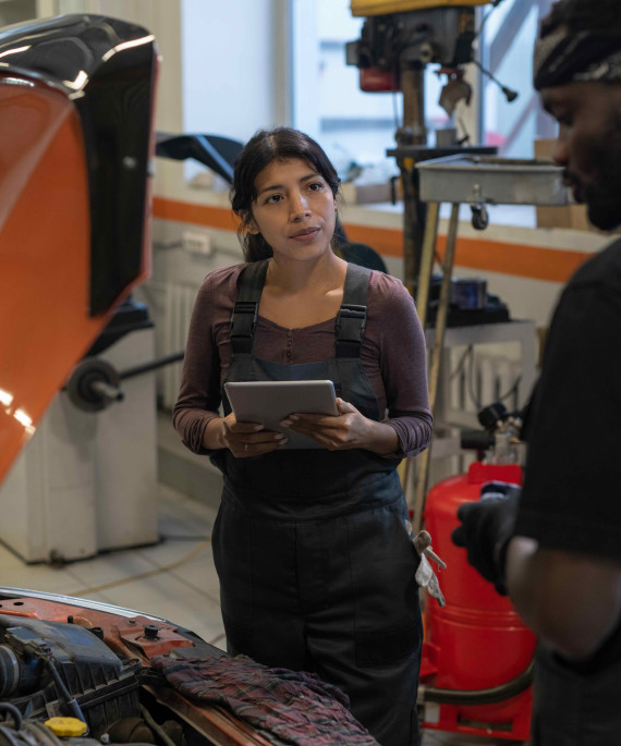 Man and woman mechanics looking at a car with the hood open