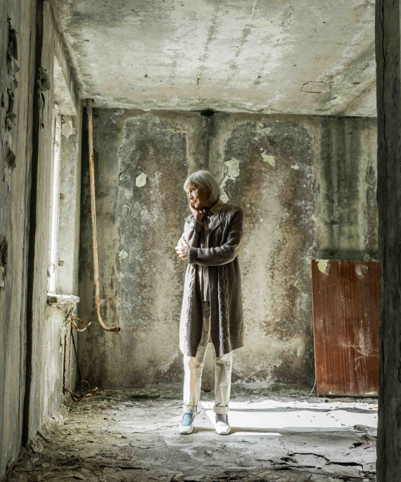 Older woman standing in a lonely building looking sad
