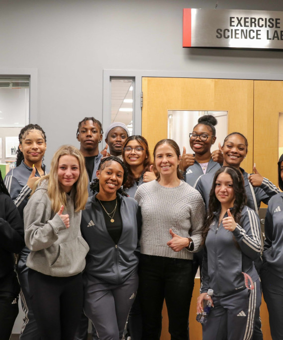 Ohio State exercise science students and professor giving thumbs up in front of lab door