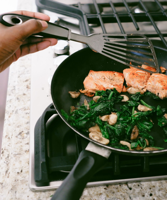 Salmon and greens being cooked in a pan on a stovetop