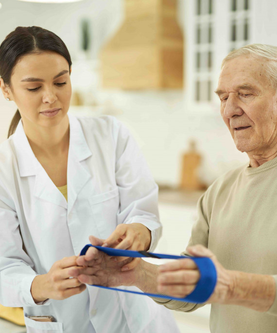 young woman assisting gray haired man with workout resistance band