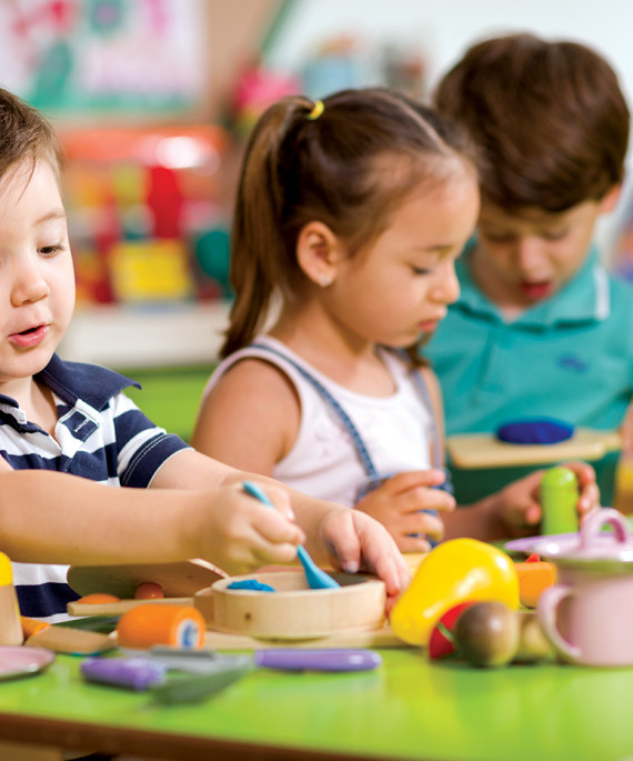 children with toy kitchen in classroom