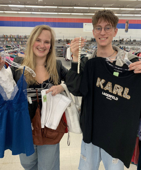 Ohio State students holding items of thrifted clothing in thrift store