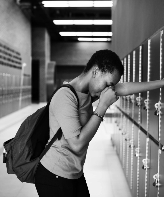 boy in school leaning against lockers in black and white