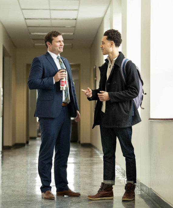 Professor and student standing in hallway talking