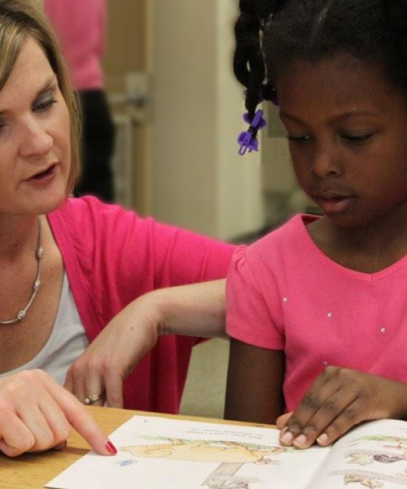 Teacher pointing to a picture on a book for a student