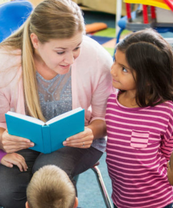 a teacher reading a book to children in a classroom