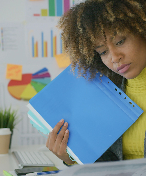 a woman is holding a binder and looking at a piece of paper