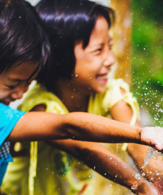 Two kids playing in a fountain