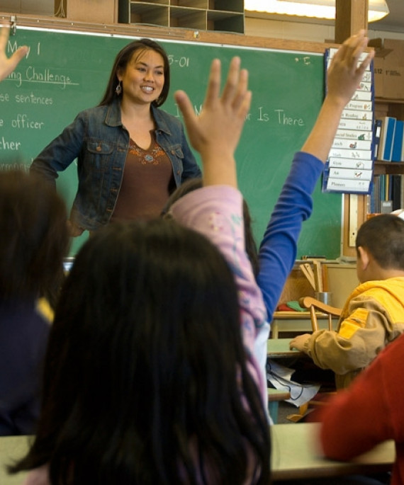 students raising hands in classroom