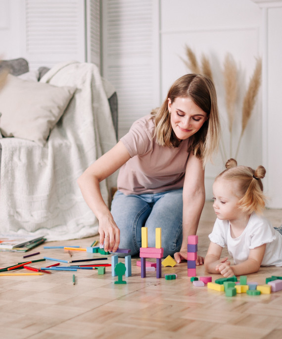 woman-and-little-girl-build-a-tower-of-wooden-colo