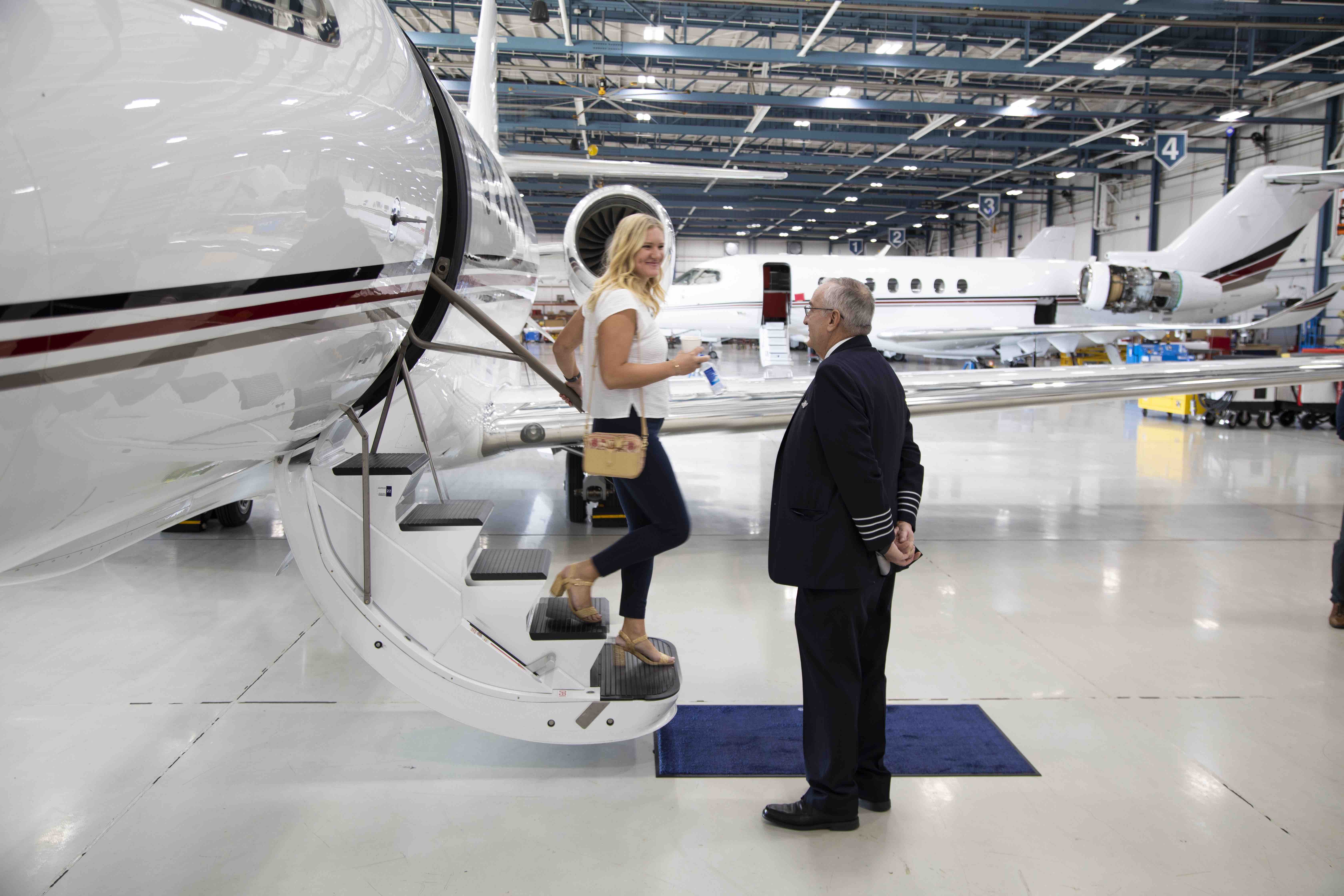 Woman stepping down from NetJet airplain in hanger with pilot