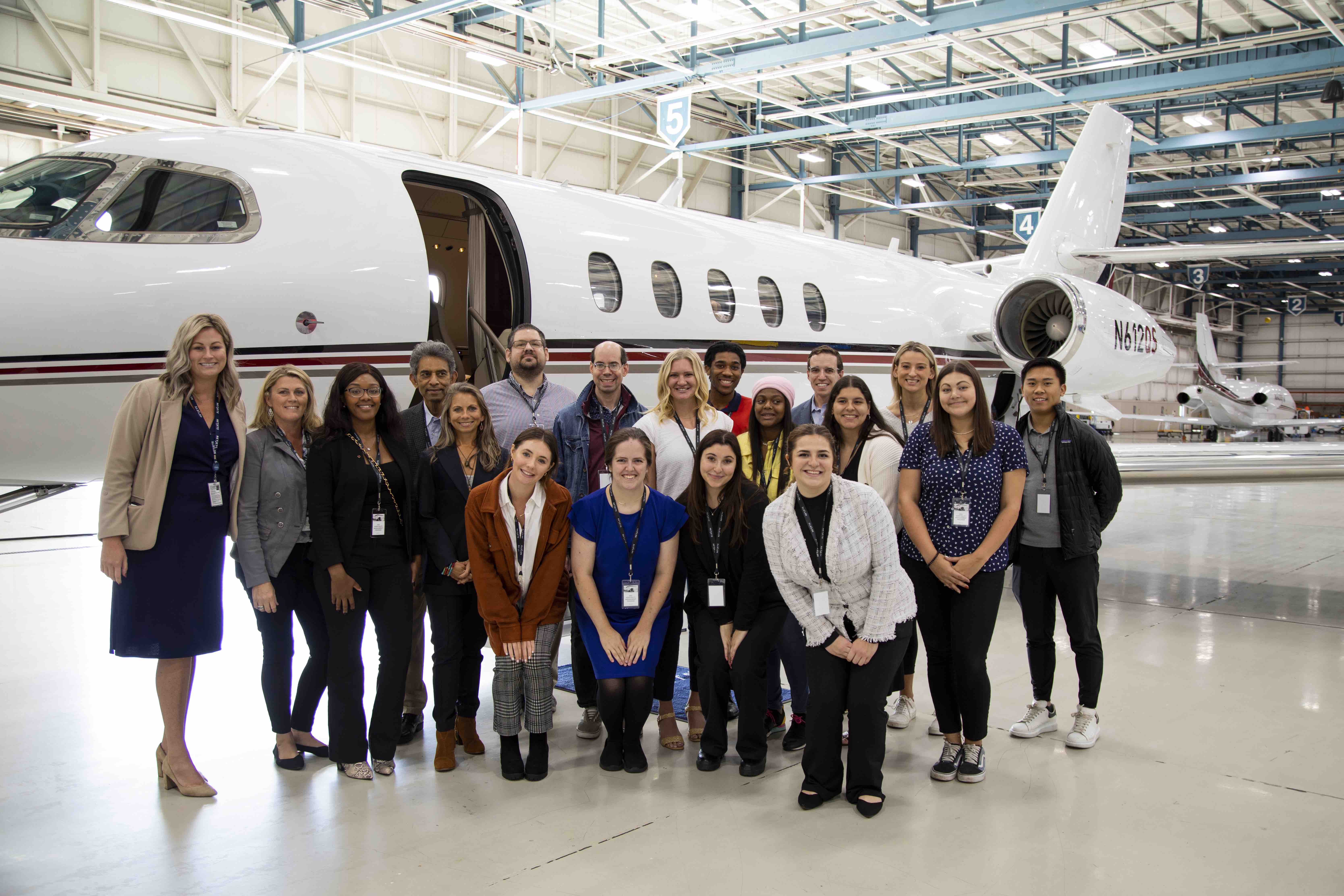 Ohio State students and NetJet employees pose for photo in airplane hanger