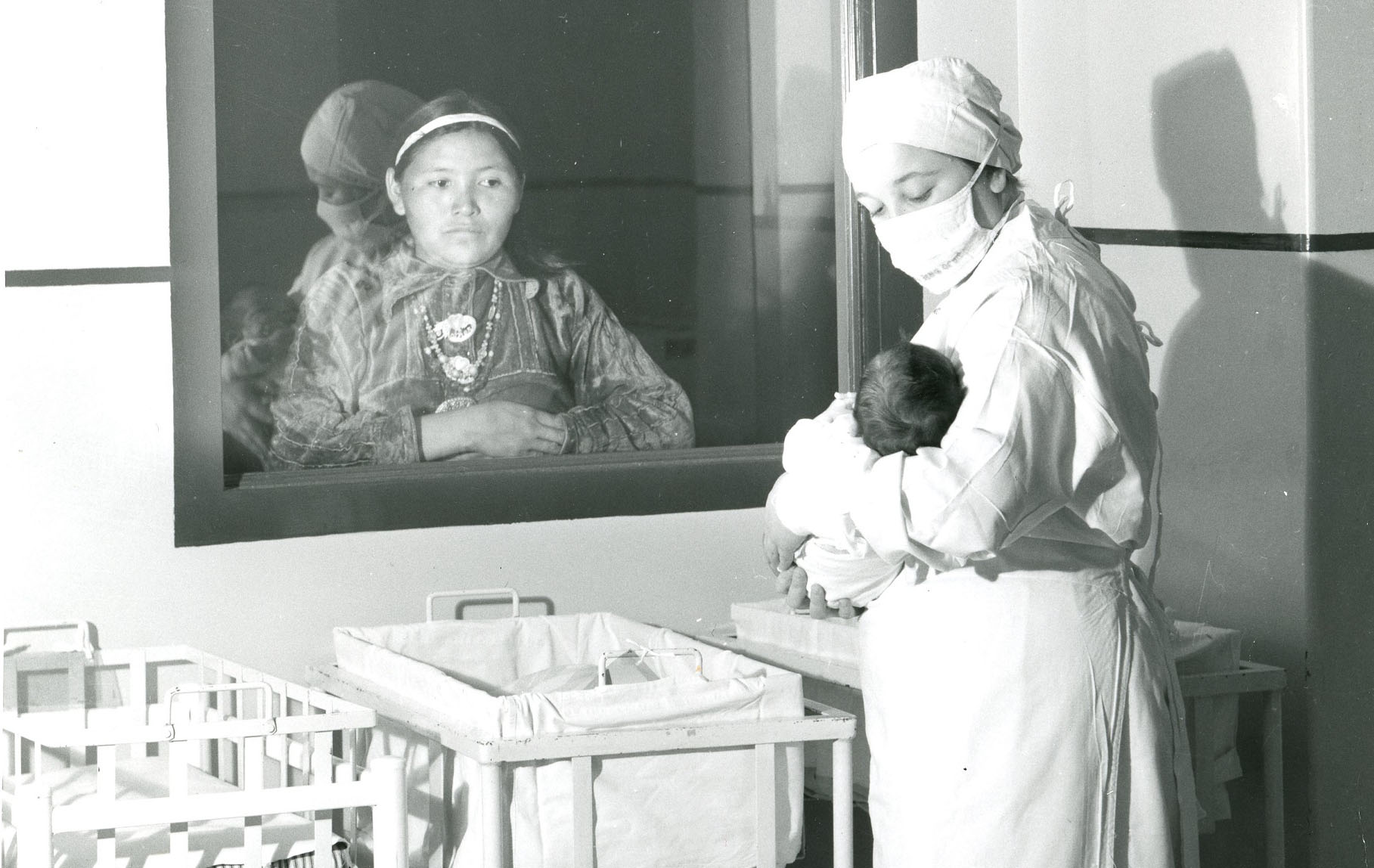 Native American mother looking through hospital window at new born baby
