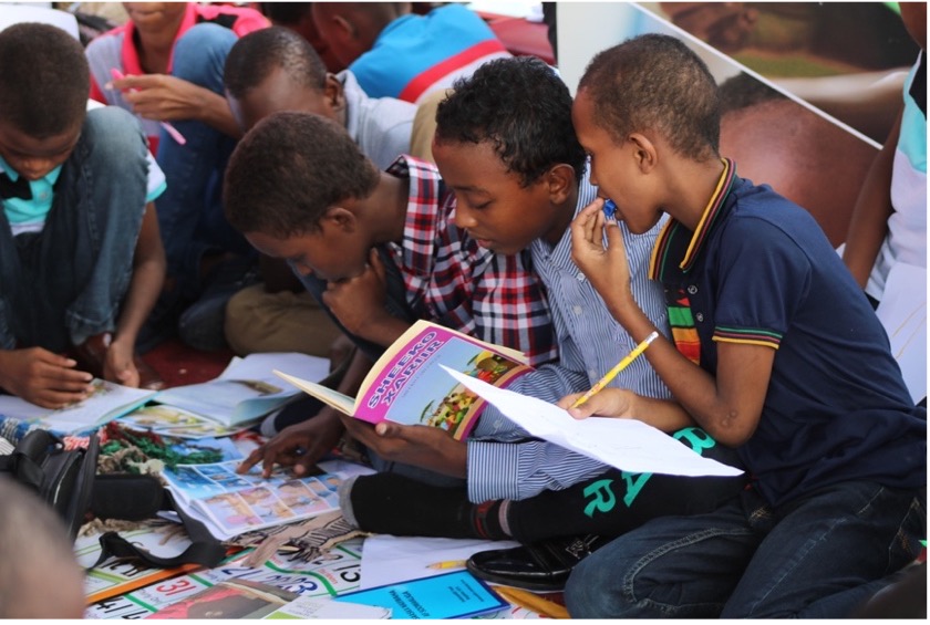 group of school children sitting on the floor reading books