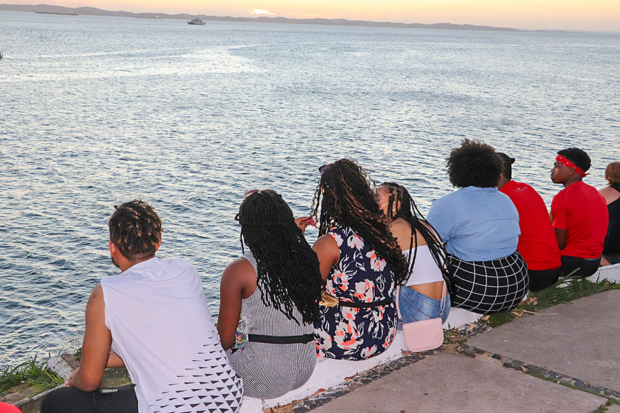 students sitting along the waters edge at sunset