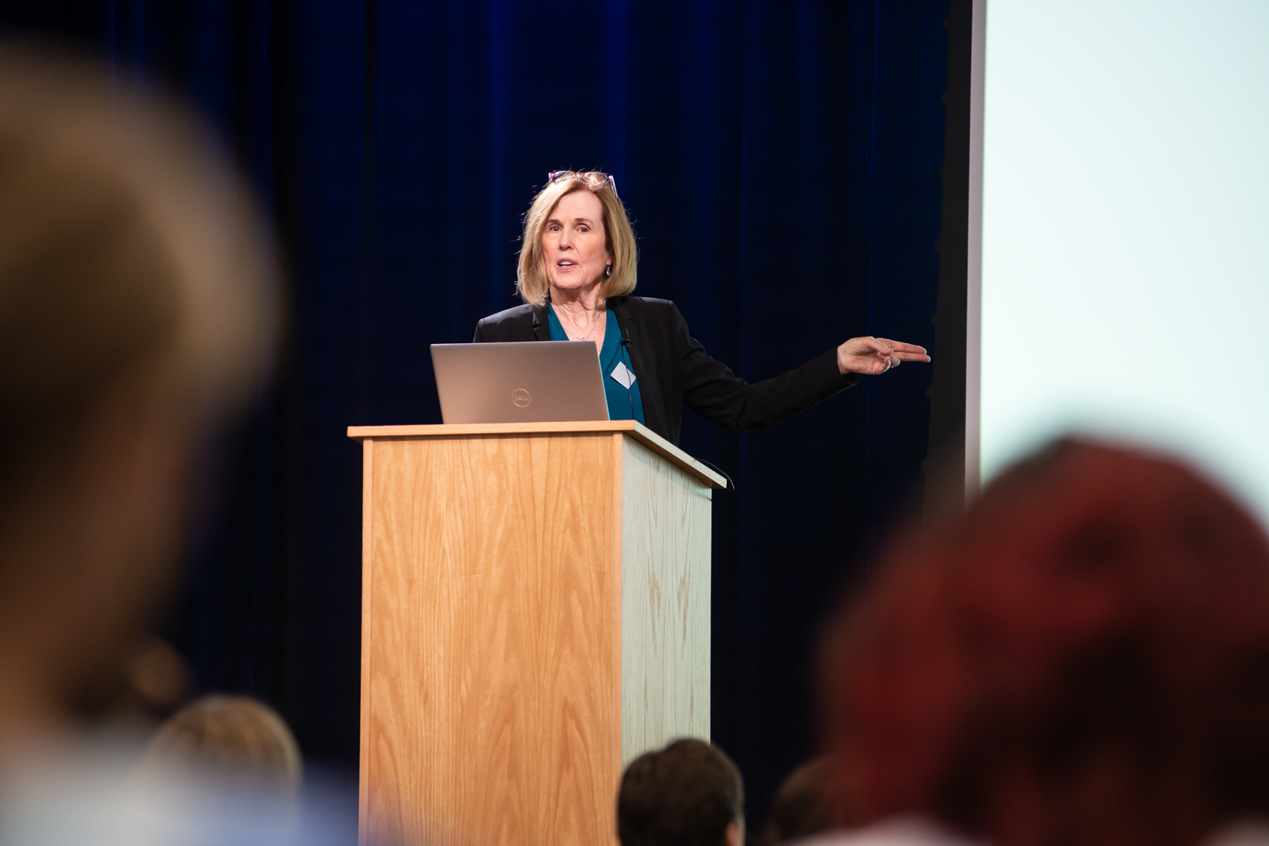 Dr. Moira Szilagyi presenting on stage behind a podium