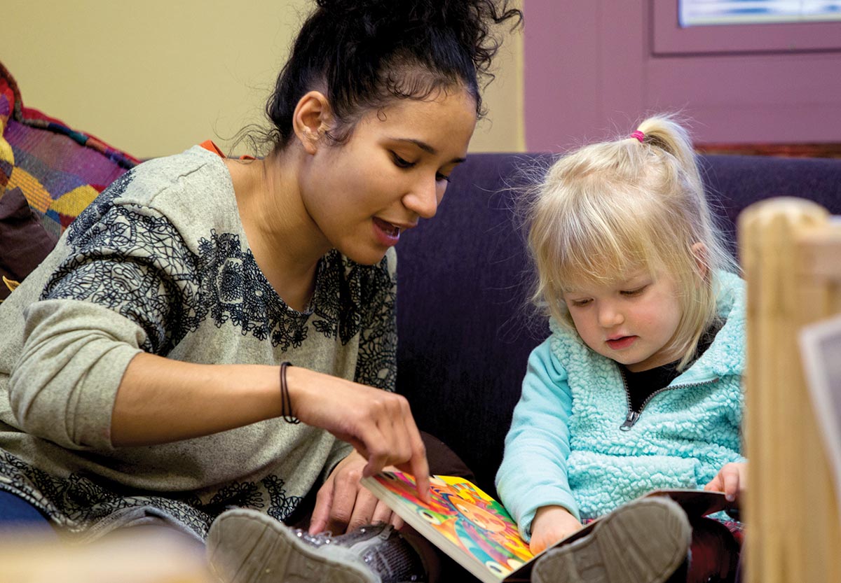 Female teacher reading picture book with young student