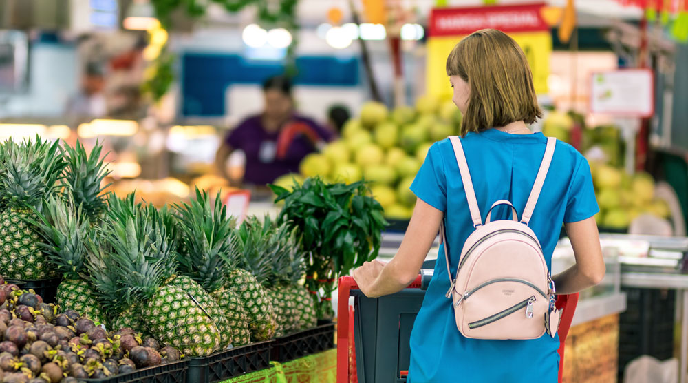Woman with backpack shops for pineapple at local market
