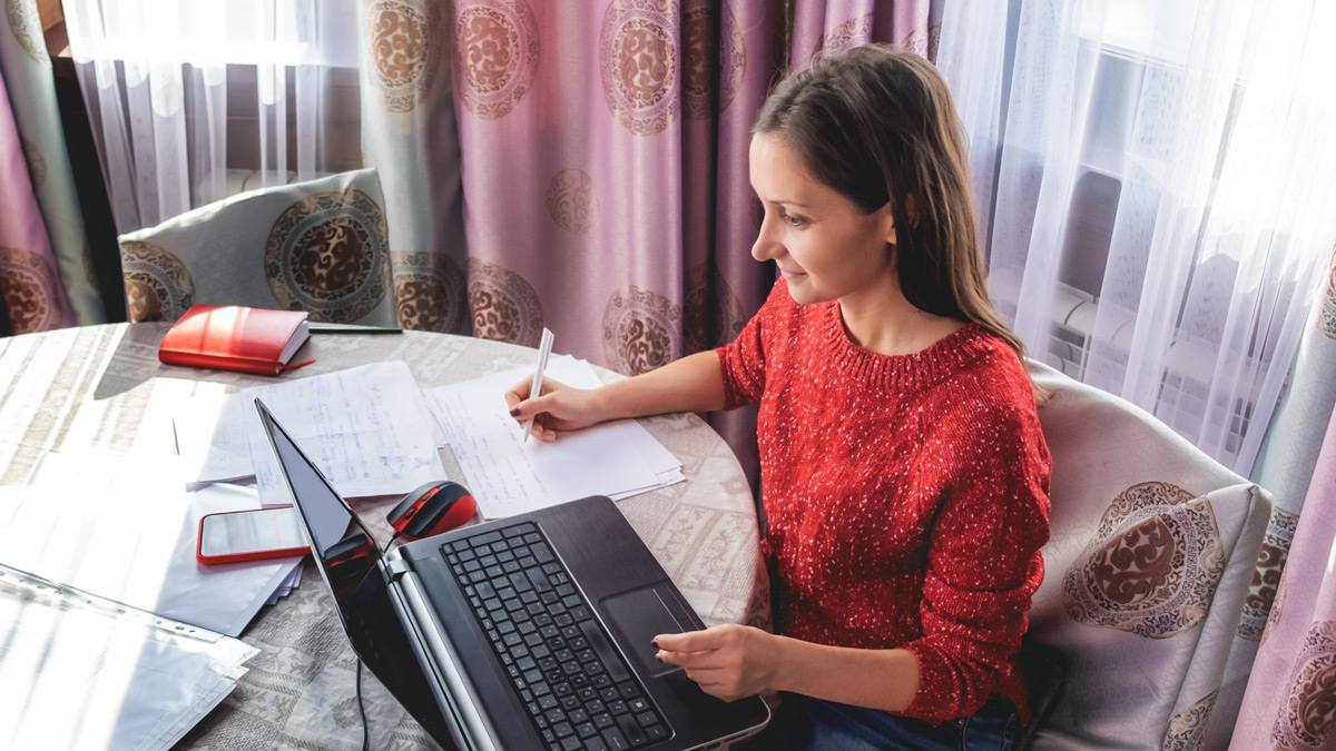 Woman working from home on laptop at dining room table