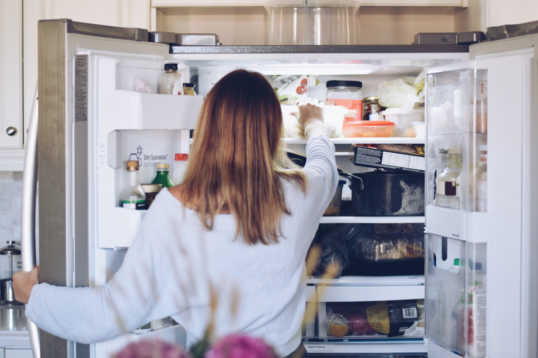 young woman taking food from refrigerator